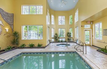 Indoor pool with hot tub and large windows